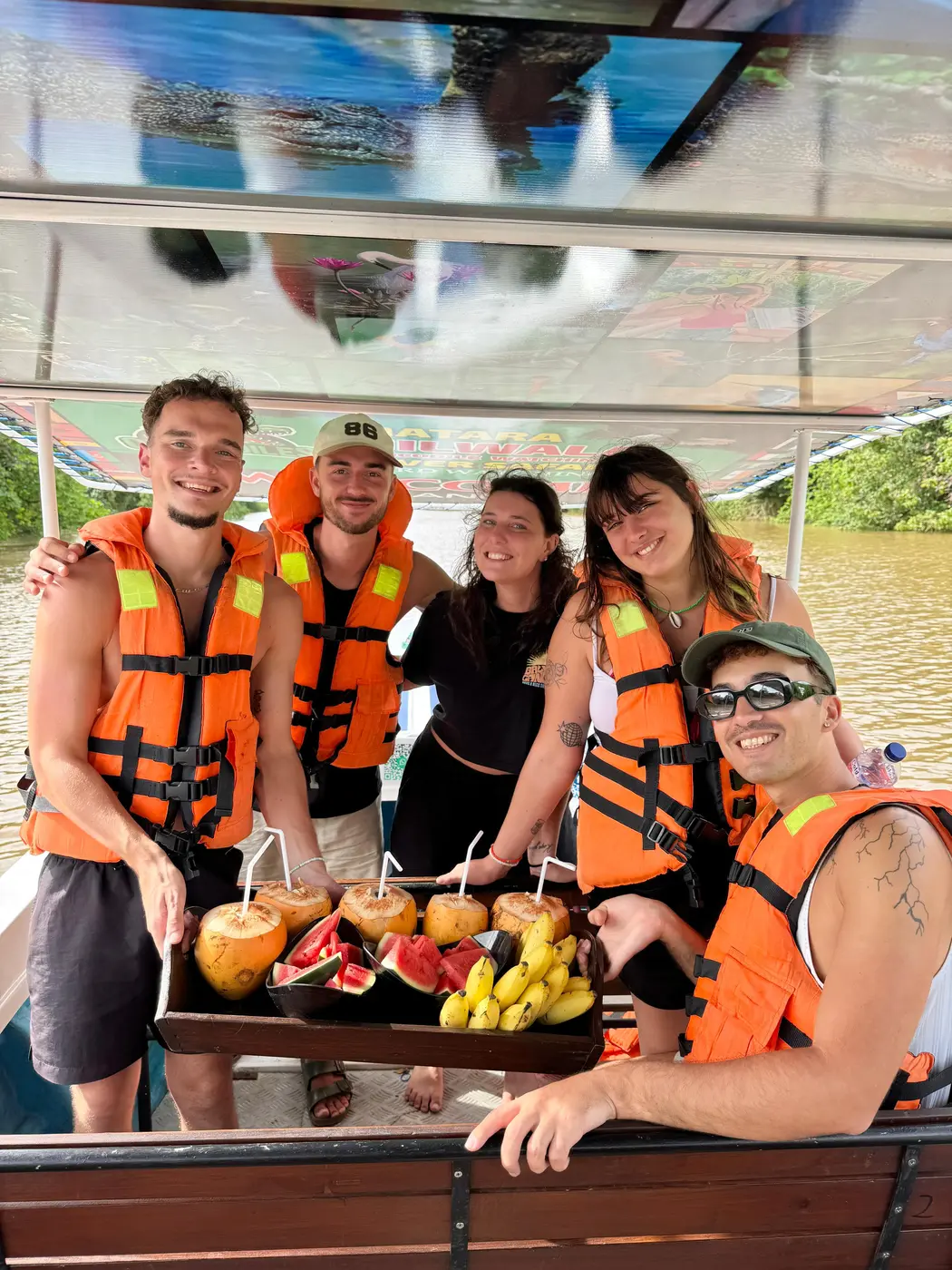 Guests in life jackets gathered around a fruit tray on the safari boat
