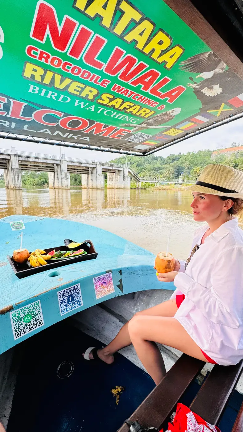 Guest seated on the boat beneath the Nilwala Crocodile Watching River Safari sign