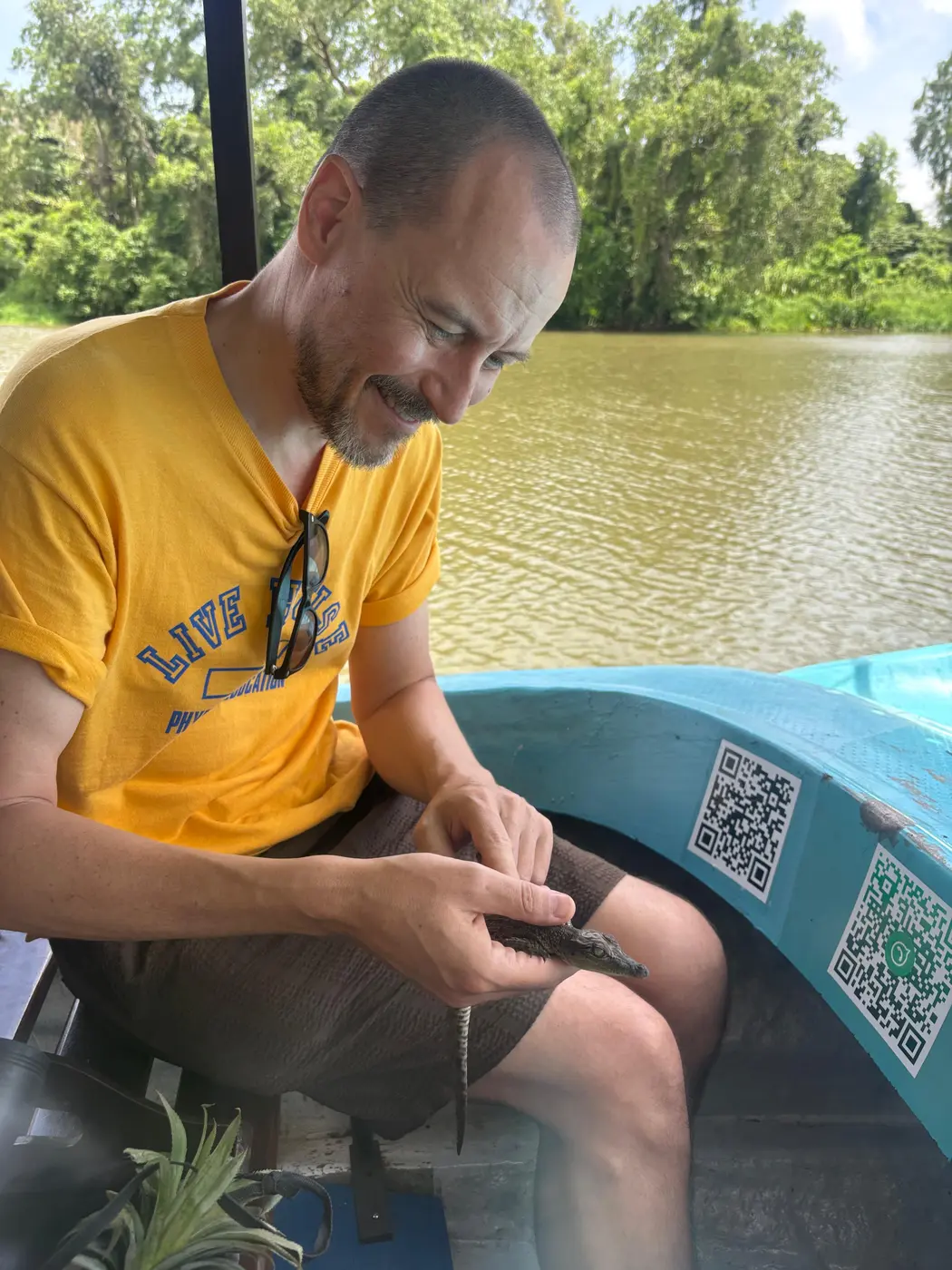Guest holding a small juvenile crocodile aboard the boat